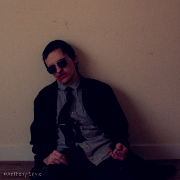 a person with short hair faking being dead with fake blood on their mouth